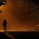 Person walking alone down a misty road at night